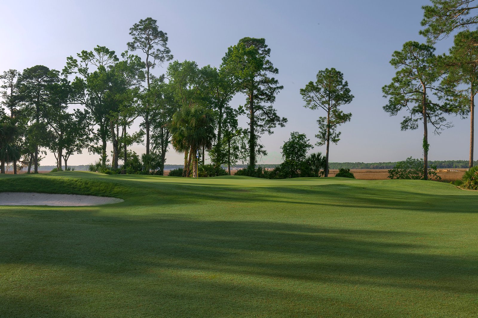 A golf course with trees and a sand trap.